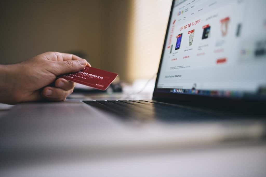 Bildschirm mit Warenkorb und eine Hand mit einer Kreditkarte