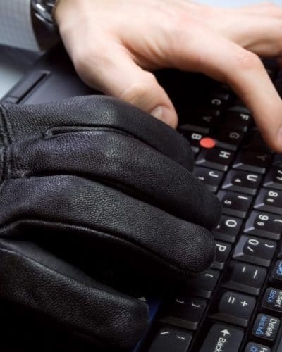 Zwei Hände auf einer Tastatur, eine davon mit Handschuh